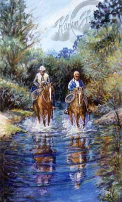 Two horse riders are riding through a blue river and the water is splashing around the horses legs with the brushy plant life around the river.