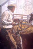 This horse backed cowboy is getting his rope ready to rope a calf in this pen by the white barn. 